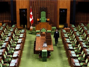 A page places calendars on the desks of members of Parliament in the House of Commons before the opening of the 44th Parliament on Nov. 22, in Ottawa on Nov. 19, 2021.