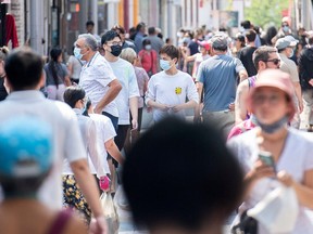 People wear face masks as they walk along a street in Montreal, Sunday, August 8, 2021, as the COVID-19 pandemic continues in Canada and around the world.