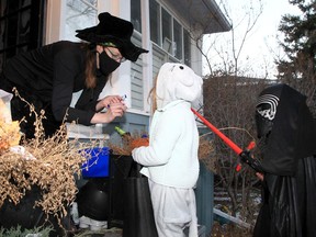 Stacie Banks dresses as a witch hands out candy to children dressed for Halloween as they enjoy a night of trick-or-treating in Crescent Heights.. Sunday, October 31, 2021.