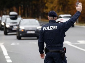 An Austrian police officer gestures towards car drivers during a traffic control at the Südring in Klagenfurt, Austria, on November 15, 2021, during the ongoing coronavirus (Covid-19) pandemic.