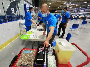 Staff prepare supplies at the pop-up COVID-19 vaccination clinic at the Village Square Leisure Centre in northeast Calgary on June 6, 2021.