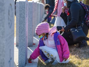 Four-year-old Hannah places poppies at the graves of soldiers at the No Stone Left Alone program at Union Cemetery on Monday, Nov. 8, 2021.