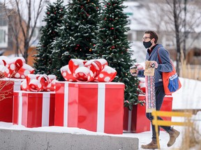 A masked pedestrian walks by the Christmas decorations in East Village on Tuesday, December 14, 2021.