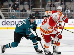 Lane Pederson of the San Jose Sharks and Trevor Lewis of the Calgary Flames battle for the puck during Tuesday night's late game at SAP Center in San Jose.