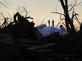People stand on a water tower that collapsed during Friday's tornado on December 13, 2021 in Mayfield, Kentucky. Multiple tornadoes touched down in several Midwest states late Friday December 10, causing widespread destruction and leaving scores of people dead and injured.