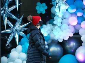 A pedestrian walks by a festively decorated window on 1st Street S.W. in downtown Calgary on Dec. 12, 2021.