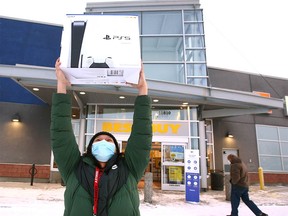 Javit Aguirre hoists a PS5 console as he leaves the Beacon Hill Best Buy store in Calgary on Sunday, December 26, 2021. Customers hit the store for Boxing Day deals.