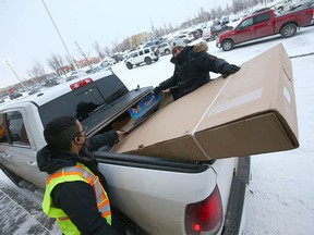 Tristan Campbell (R) gets a hand loading his new TV into a truck from staff at the Beacon Hill Best Buy store in Calgary on Sunday, December 26, 2021. Campbell has been saving his gift cards for 2-3 years (approximately $1,400) and had enough for the new TV.