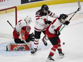 Team Canada's Jake Neighbours (12) battles Team Austria's Marco Kasper (19) in front of goalie Leon Sommer (1) during second period IIHF World Junior Hockey Championship action in Edmonton on Tuesday, Dec. 28, 2021.