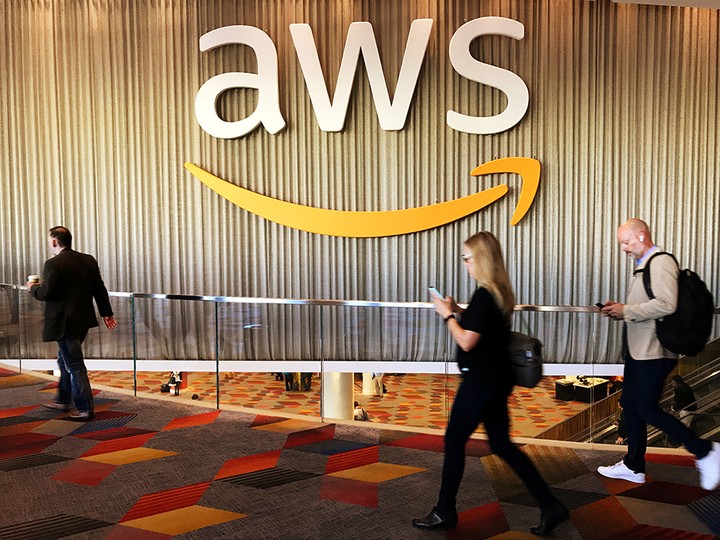  Attendees at Amazon’s annual cloud computing conference walk past the Amazon Web Services logo in Las Vegas on Nov. 30, 2017.