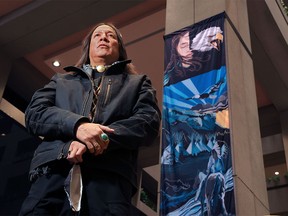 Blackfoot artist Kalum Teke Dan stands in front one of the three banners he created being installed on pillars in the atrium of Calgary City Hall on Thursday, December 16, 2021. The pieces titled Past, Present and Future portray the rich history of the land on which Calgary now sits and how all people are working to understand the wrongs of the past and provide a way forward for the future.