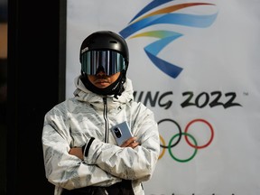 A snowboarder stands in front of the Beijing 2022 Winter Olympics logo in Zhangjiakou, Hebei province, China, on Nov. 20, 2021.