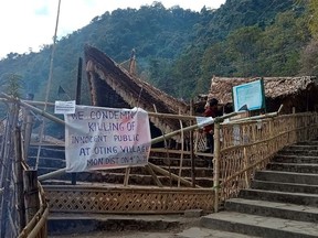 A man walks behind a placard posted at the venue of the Hornbill festival which was shut after Indian security forces killed 13 civilians in the northeastern state of Nagaland firing on a truck and later shooting at a crowd that gathered to protest the attack, at Kisama village in Kohima on Dec. 5, 2021.