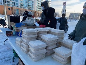 Volunteers with Bear Clan Patrol Calgary hand out turkey dinners and other emergency supplies to people who are unhoused outside the Drop In Centre in Calgary on Christmas Day.