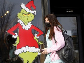 Sofia Leuchter walks by a store window while Christmas shopping on 11 St. S.W. COVID cases continue to rise in Calgary as Omicron threatens to play the role of Grinch in upcoming holiday celebrations.