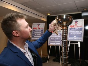 Jesse Hale, GM of the Mac's U18AAA hockey tournament, polishes the winner's trophy.
