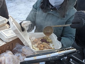 Volunteers with Bear Clan Patrol Calgary hand out turkey dinners and other emergency supplies to people who are unhoused outside the Drop-In Centre in Calgary on Christmas Day.
