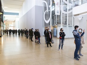 A lengthy queue snakes though Toronto's Yorkdale Mall as people wait to receive a free COVID-19 rapid antigen test kit on Thursday, Dec. 16, 2021.