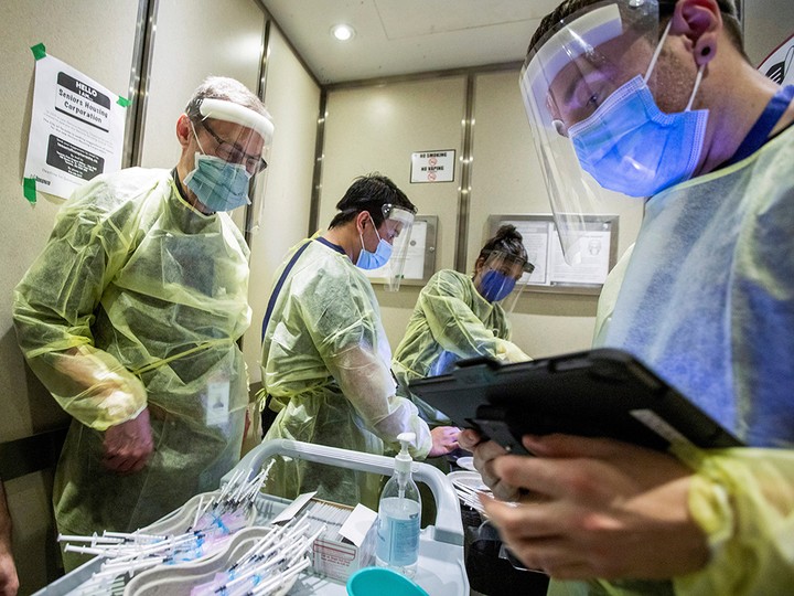  Nurses and doctors ride an elevator as they prepare to administer COVID-19 vaccines at a Toronto Community Housing seniors building on March 25, 2021.