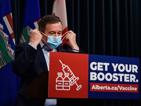 Premier Jason Kenney takes off his mask before providing an update on Alberta’s COVID-19 response at the McDougall Centre on Tuesday, January 4, 2022.