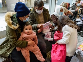 Malika Haidari, left, and Hussain Negah and their children, six-month old Keivan and Zohal, 6, receive winter clothing after arriving in the Calgary International Airport (YYC) as Government Assisted Refugees (GAR) from Afghanistan on Tuesday, January 11, 2022. Heidari used to work as a public health doctor and Negah an economist at their home country. The Negahs, along with around 250 newcomers are helped by Calgary Catholic Immigration Society (CCIS) staff to receive winter clothing before heading to the hotel where they quarantine.