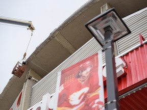 Workers attach a cover around the Scotiabank Saddledome on Wednesday, Jan. 12, 2022.