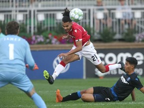 Cavalry FC’s Mo Farsi gets a shot away over Edmonton FC defender Paris Gee in front of keeper Connor James during a CPL match at ATCO Field at Spruce Meadows on Aug. 3, 2021.