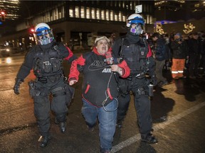 A demonstrator who was taking part in an anti-curfew protest in Montreal on Jan. 1, 2022, is taken away by police