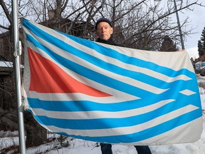 Calgary graphic designer John Vickers stands with the proposed new flag for Calgary that his company designed on Thursday, January 13, 2022. The flag, featuring six converging diagonal blue lines, is meant to represent the confluence of the Bow and Elbow rivers as well as the Treaty 7 Nations.