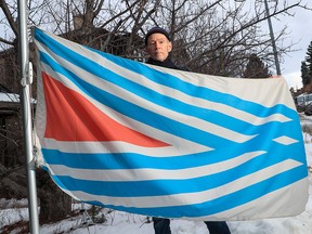 Calgary graphic designer John Vickers stands with the proposed new flag for Calgary that his company designed on Thursday, January 13, 2022. The flag, featuring six converging diagonal blue lines, is meant to represent the confluence of the Bow and Elbow Rivers as well as the Treaty 7 Nations.