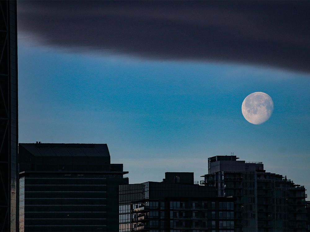 The moon sets as a chinook arch moves in over Calgary after sunrise on Thursday, January 20, 2022.