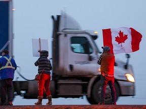 Supporters of the “freedom convoy” of truckers wait for the convoy along the Trans-Canada Highway east of Calgary on Monday, January 24, 2022. The truckers are driving across Canada to Ottawa to protest the federal government’s COVID-19 vaccine mandate for cross-border truckers.