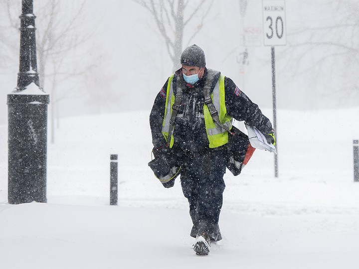  A Canada Post worker delivers mail during a snowstorm in Montreal, Monday, January 17, 2022.