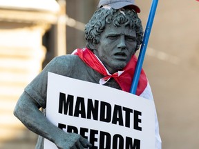 A statue of Terry Fox is altered with a Canadian flag, protest sign and cap during a protest against vaccine mandates on Parliament Hill in Ottawa on Saturday, Jan. 29, 2022.
