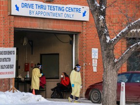 Alberta Health Services staff conduct drive-through COVID-19 tests at the Richmond Road testing site in Calgary on Dec. 30, 2021.