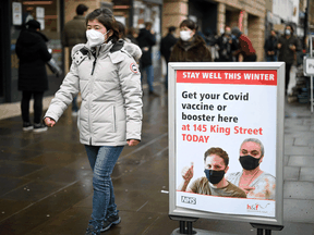 A woman walks past a sign outside a COVID-19 vaccination centre in London, England. In a U.K. study, researchers found about two-thirds of participants who tested positive in January reported being previously infection with COVID.