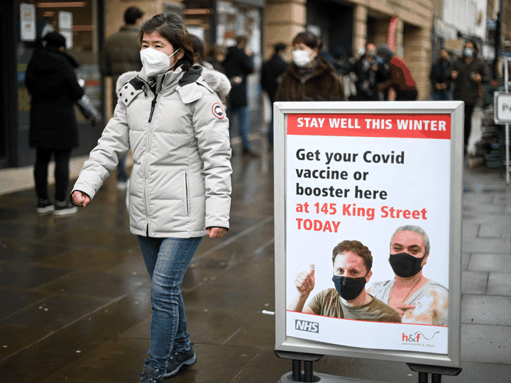  A woman walks past a sign outside a COVID-19 vaccination centre in London, England. In a U.K. study, researchers found about two-thirds of participants who tested positive in January reported being previously infection with COVID.