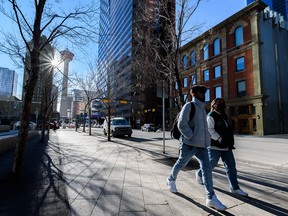 Pedestrians walk along Centre Street in downtown Calgary on a sunny afternoon on Friday, Jan. 21, 2022.