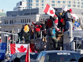 Protestors stand on a trailer carrying logs as truckers and supporters take part in a convoy to protest coronavirus disease (COVID-19) vaccine mandates for cross-border truck drivers in Ottawa, Ontario, Canada, January 29, 2022.