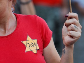 A protester wears a Second World War emblem depicting the star of David badge with a German word "Jude" (Jew) in Rome, Italy, in 2021.
