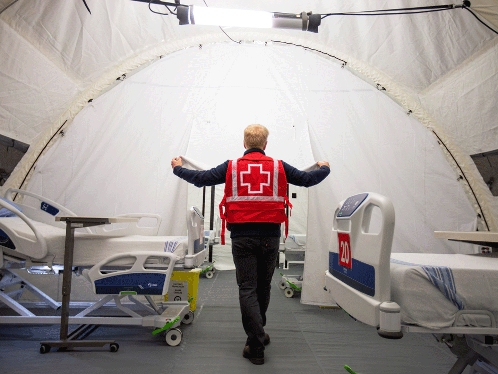  A Red Cross volunteer walks between beds in a mobile hospital set up to help care for COVID-19 patients in Montreal, April 26, 2020. Hospitals in Quebec and Ontario are currently being pushed to the breaking point by the effects of the Omicron variant.