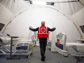 A Red Cross volunteer walks between beds in a mobile hospital set up to help care for COVID-19 patients in Montreal, April 26, 2020.