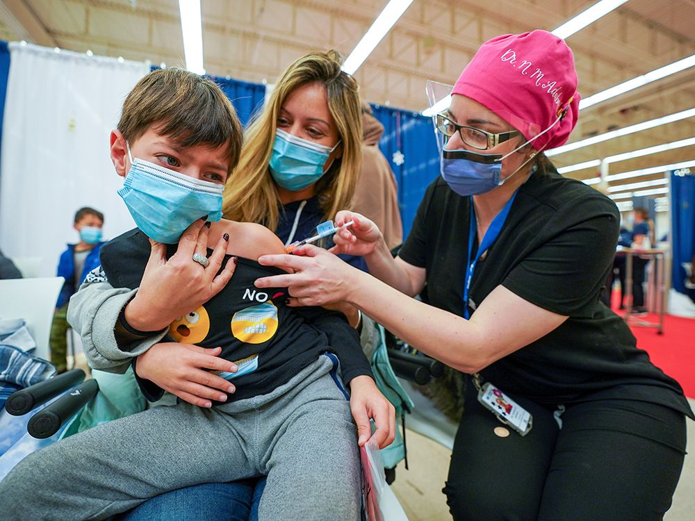  Dean Eliaz is comforted by his mom Michelle Eliaz as he gets his shot at a COVID-19 vaccination clinic in Toronto on Nov. 25, 2021.