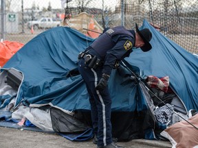 Peace officers are at the scene as the homeless at the camp outside the Calgary Drop-in Centre are helped by staff and volunteers prior to being removed by the Calgary Police on Thursday, February 10, 2022.