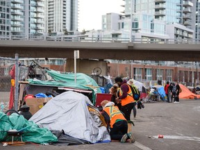 The homeless in tents outside the Calgary Drop-in Centre are helped by staff and volunteers prior to being removed by Calgary police on Thursday, Feb. 10, 2022.