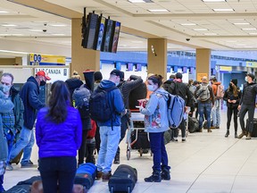 People wait in line to check in their luggage before their flight at Calgary International Airport (YYC) on Tuesday, February 22, 2022.