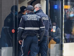 A transit peace officer and a Calgary police officer board a CTrain at City Hall station on February 28, 2022.