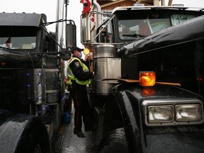 A police officer climbs into the passenger seat of a honking truck in Ottawa on Thursday.