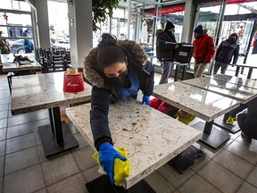 In preparation of the reopening of eating inside restaurants, a worker at Cafe Diplomatico Restaurant & Pizzeria cleans tables on Sunday January 30, 2022