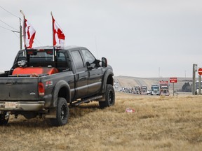 Supporters look on as anti-COVID-19 vaccine mandate demonstrators leave in a truck convoy after blocking the highway at the busy U.S. border crossing in Coutts, Alta., Tuesday, Feb. 15, 2022.